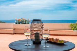 twee glazen wijn en een bord eten op tafel bij Hotel Baia Imperiale in Campo nell'Elba