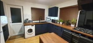 a kitchen with blue cabinets and a washing machine at Cosy room Maidstone in Kent