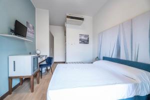 a bedroom with a bed and a desk and a tv at Hotel Baia Imperiale in Campo nell'Elba