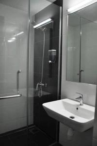 a bathroom with a sink and a shower with a mirror at Temasek Hotel in Melaka