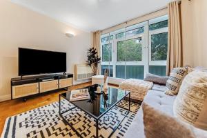 ein Wohnzimmer mit einem Sofa und einem TV in der Unterkunft Unique 2 bed 2 bath Victorian flat Regents Park in London