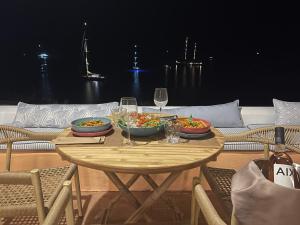 uma mesa de madeira com duas taças de comida e taças de vinho em Lipsi Blue Hotel em Lipsoi