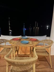 Lipsi Blue Hotel في ليبسوي: طاولة خشبية عليها اربعة اطباق مع كراسي