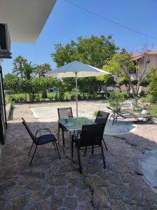 patio con tavolo, sedie e ombrellone di Nikilein's House, διαμέρισμα 150μ απο την παραλία a Roda