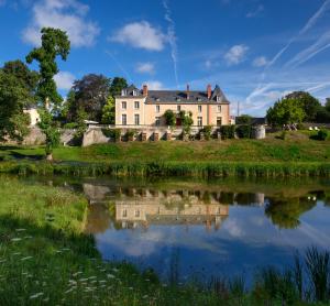 una casa grande en una colina junto a un lago en Château de la Huberdière, en Nazelles