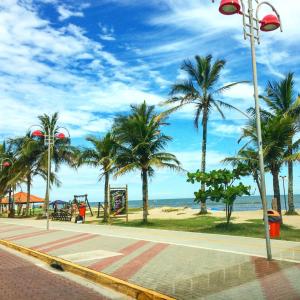 a street with palm trees and a playground on the beach at Rial Hotel in Itanhaém