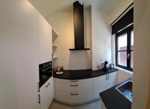 a kitchen with white cabinets and a stove top oven at Huis ALNA 3 in Mechelen