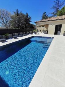 una piscina azul con sillas y una casa en GRAND GîTE AUGUSTA, en Ruoms