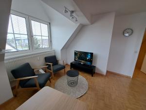 a living room with two chairs and a flat screen tv at Flataid Apartments Gössendorf/Magna 