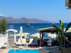 a swimming pool with chairs and umbrellas and the ocean at Hotel Turun&ccedil;-Malmen in Turunc