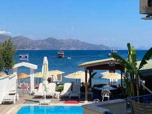 a swimming pool with chairs and umbrellas and the ocean at Hotel Turunç-Malmen in Turunç