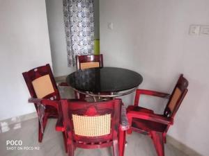 un tavolo e quattro sedie rosse in una stanza di Munnar Hills & Mist View a Anachal