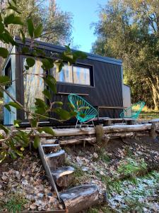 Hermosa Tiny House con Vista al Chapelco في سان مارتين دي لوس أندس: منزل صغير على رصيف خشبي مع كراسي