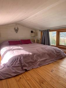 un grande letto in una camera con pavimento in legno di Hermosa Tiny House con Vista al Chapelco a San Martín de los Andes