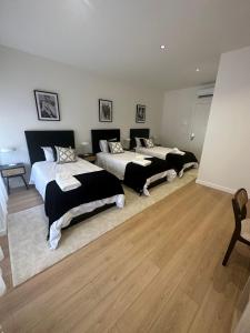 a bedroom with two beds and a wooden floor at Apartamentos sobre o Douro in Porto