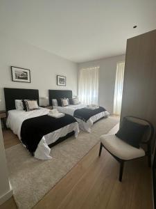 a bedroom with two beds and a chair in it at Apartamentos sobre o Douro in Porto