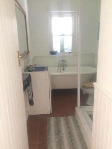 ein Badezimmer mit einer Badewanne, einem WC und einem Waschbecken in der Unterkunft Rustic Beach House 300 Steps from the Ocean in Kapstadt