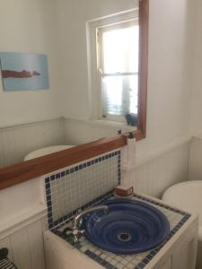a bathroom with a sink with a blue plate in it at Rustic Beach House 300 Steps from the Ocean in Cape Town