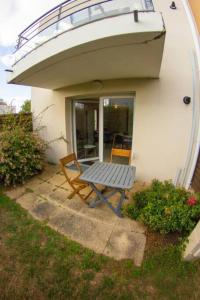 une table et une chaise assises sous un balcon dans l'établissement Studio le Flamboyant, à Cholet