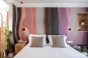 ein Schlafzimmer mit einem weißen Bett mit einer farbenfrohen Wand in der Unterkunft Oborishte 63,The Art Boutique Hotel by Sandglass in Sofia