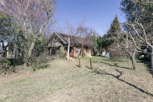 a house in a field with a yard with trees at Pai Pay Calido y Confortable Bungalow in San Carlos de Bariloche
