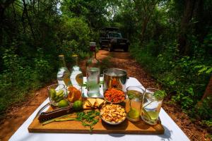 uma mesa com garrafas de vinho e comida num trilho em Kulu Safaris - All Inclusive em Yala