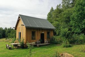 a wooden cabin with a solar roof in a field at Olejarnia Godki in Jonkowo