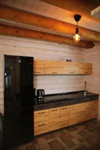 a kitchen with a black refrigerator and wooden walls at Žaliūkių pirtis in Žaliukai