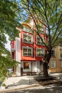 un edificio rojo con un árbol delante de él en Oborishte 63,The Art Boutique Hotel by Sandglass en Sofía