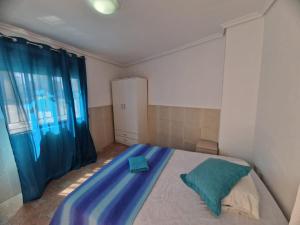 a bedroom with a bed with blue sheets and a window at Casa Alboraya Valencia in Alboraya