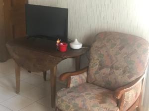 a chair sitting next to a table with a television at Au soleil du Der in Joncreuil