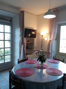a dining room table with four chairs and a vase of flowers at Mas du Bosc in Rosières
