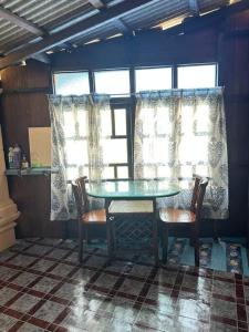 une table et des chaises dans une pièce avec fenêtres dans l'établissement Warisan Homestay Anjung, à Mersing