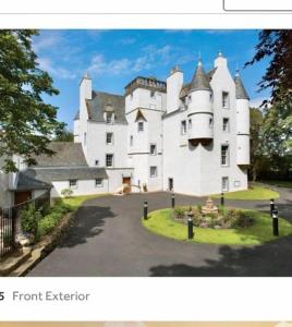 un gran castillo blanco sentado en la parte superior de una entrada en Castle Gogar Cottage en Edimburgo