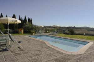 a swimming pool with an umbrella and chairs and a table at Appartamenti Casalsole in Cerreto Guidi