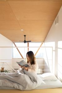 a woman sitting on a bed reading a book at FUN - Vacation STAY 48765v in Kanazawa