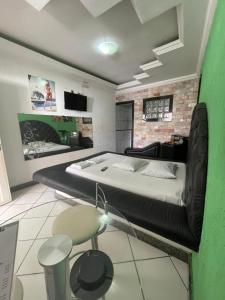 1 dormitorio con 1 cama grande y pared de ladrillo en 24 Horas Motel Jaguar Contagem, en Contagem