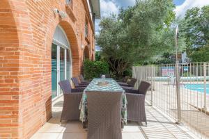 a patio with a table and chairs and a pool at Appart'City Classic Toulouse Colomiers in Colomiers