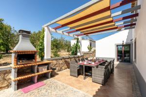 eine Terrasse mit einem Grill, einem Tisch und Stühlen in der Unterkunft Villa Rodrigues in Boliqueime