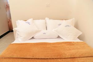una cama con almohadas blancas encima en Scindia Suites hotel, en Jinja