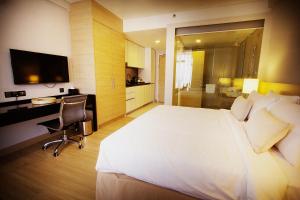 ein Hotelzimmer mit einem großen weißen Bett und einem Schreibtisch in der Unterkunft The Straits Hotel & Suites in Malakka