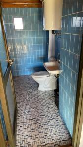 a blue tiled bathroom with a toilet and a sink at Sommerhus, Hornbæk in Hornbæk