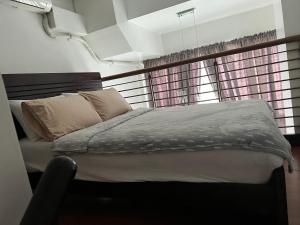 a bed in a room with two windows at Eton Emerald Loft ortigas in Manila