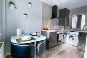 eine Küche mit einem Tisch und einer Waschmaschine in der Unterkunft Modern Home, Beautiful Spacious Garden, City Centre NETFLIX in Manchester