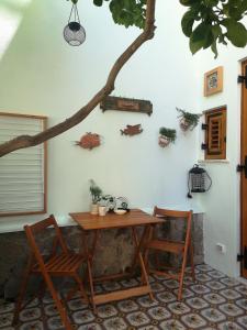 un tavolo e due sedie e un albero su un muro di Al Limone a Città di Lipari
