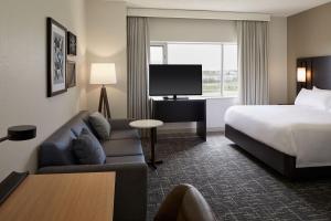 a hotel room with a bed and a couch and a tv at Residence Inn by Marriott Montreal Airport in Dorval