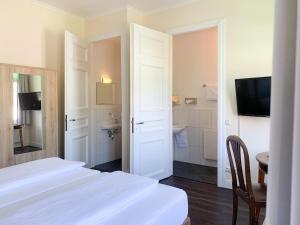 a white bedroom with two beds and a bathroom at 2T Hotel artgenossen in Lindlar