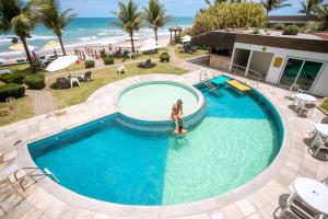 a woman standing in a swimming pool next to the beach at Kembali Hotel Porto de Galinhas - Adults Only in Porto De Galinhas