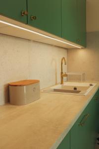 a kitchen with green cabinets and a sink and a counter at Malta Lake - Apartment in Poznań