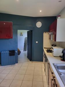 eine Küche mit blauen Wänden und einer Uhr an der Wand in der Unterkunft Le champ neuf in Saint-Julien-des-Points